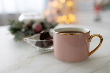 Pink cup with coffee and chocolate in a glass vase on the table. Bokeh. Photo