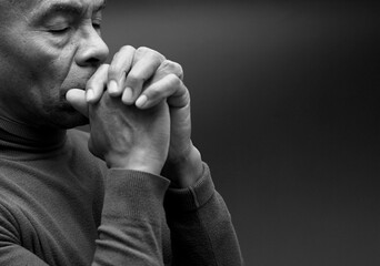 man praying to god with hands together Caribbean man praying with black background with people stock photo