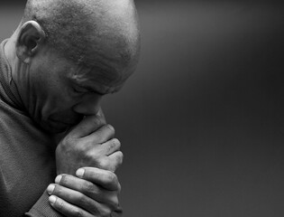 man praying to god with hands together Caribbean man praying with black background with people stock photo