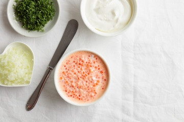 Red caviar with sour cream, dill and onion - the finnish recipe for a holiday food, flat lay on the white table in minimalistic style with copy space