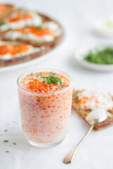 Appetizer with red caviar, sour cream, dill, onion and rye bread on the white table - the finnish recipe for a holiday food, close up in minimalistic style
