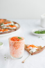 Appetizer with red caviar, sour cream, dill, onion and rye bread on the white table - the finnish recipe for a holiday food, close up in minimalistic style