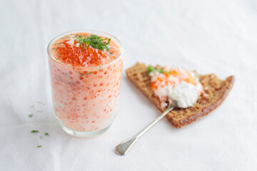 Appetizer with red caviar, sour cream, dill, onion and rye bread on the white table - the finnish recipe for a holiday food, close up in minimalistic style