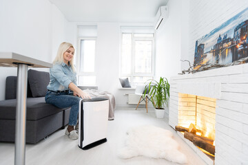 Woman relaxing at home with working air humidifier on the foreground. Concept of home air humidification