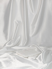 the stand made of white stone lies on a white satin draped background 