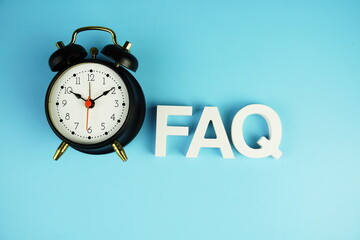 FAQ alphabet letters with alarm clock top view on blue background