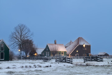 Wooden farmhouse covered with snow in the small village of Zaanse Schans in the evening.