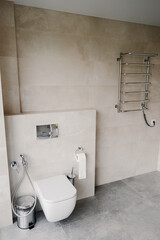 Interior of a modern toilet with hidden installation against a light wall. Heated towel rail on the...