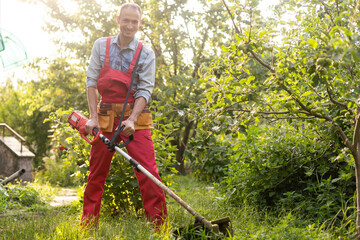 Mowing grass with electric lawn mower. Garden work concept. Man mows the grass with hand mower in...