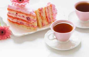 two cups of tea with pink cake on white table
