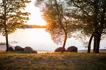 lakeside retreat at sunset with golden light piercing through the trees and reflecting on the calm...