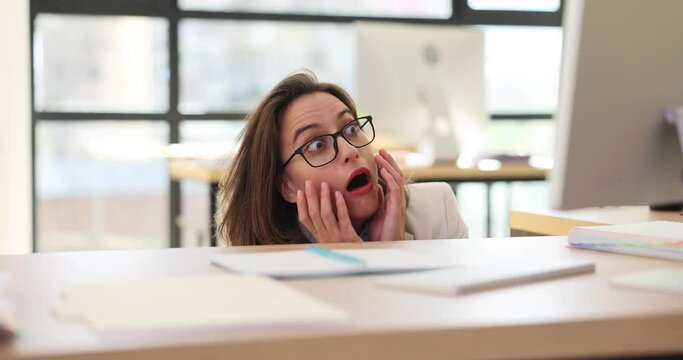 Frightened businesswoman in glasses hiding under table and looking at computer monitor 4k movie slow motion