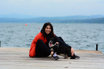 Woman Hugging her Adopted Black Dog on a Lake Background 