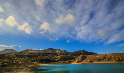 Lake in the mountains under a blue cloudy sky
