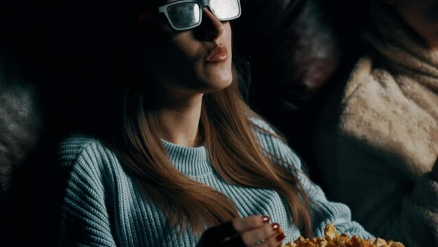 Couple in love A guy and a girl eat popcorn and watch a movie in a cinema using 3D glasses. Concept of a movie show in a cinema