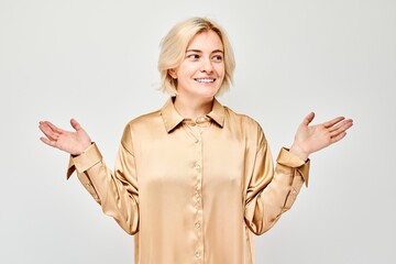 Young blond woman in casual holding something in hand, demonstrating empty space for product or...