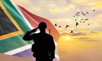 Silhouette of a soldier with the South Africa flag stands against the background of a sunset or...