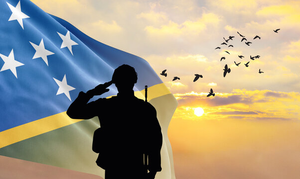Silhouette of a soldier with the Solomon Islands flag stands against the background of a sunset or sunrise. Concept of national holidays. Commemoration Day.