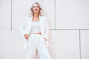 Young beautiful blond woman wearing nice trendy white suit jacket. Smiling model posing in the...