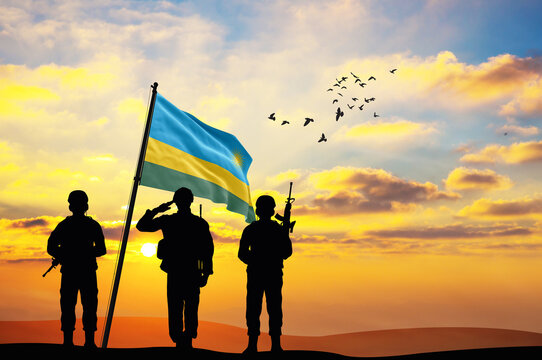 Silhouettes of soldiers with the Rwanda flag stand against the background of a sunset or sunrise. Concept of national holidays. Commemoration Day.