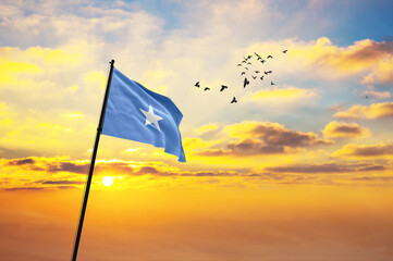 Waving flag of Somalia against the background of a sunset or sunrise. Somalia flag for Independence Day. The symbol of the state on wavy fabric.