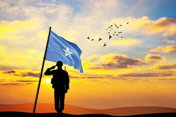 Silhouette of a soldier with the Somalia flag stands against the background of a sunset or sunrise. Concept of national holidays. Commemoration Day.