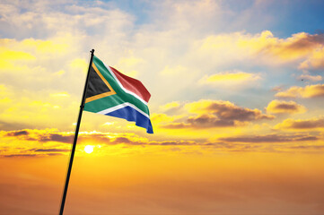 Waving flag of South Africa against the background of a sunset or sunrise. South Africa flag for Independence Day. The symbol of the state on wavy fabric. - obrazy, fototapety, plakaty