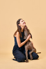 Hugs and kisses, dogfriendly. Lifestyle. Young brunette woman sitting on floor and hugs with her...