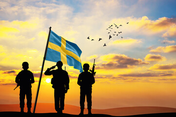 Silhouettes of soldiers with the Sweden flag stand against the background of a sunset or sunrise. Concept of national holidays. Commemoration Day.