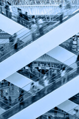 People on many fast moving escalators in modern shopping mall