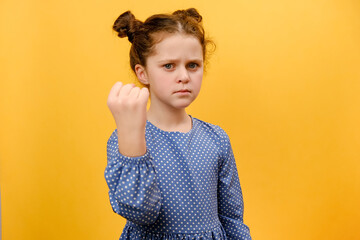 Portrait of aggressive angry little girl kid trying to fight at camera, shaking fist, boxing with...