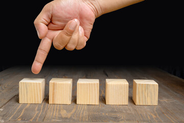 A human hand shows a row of wooden cubes