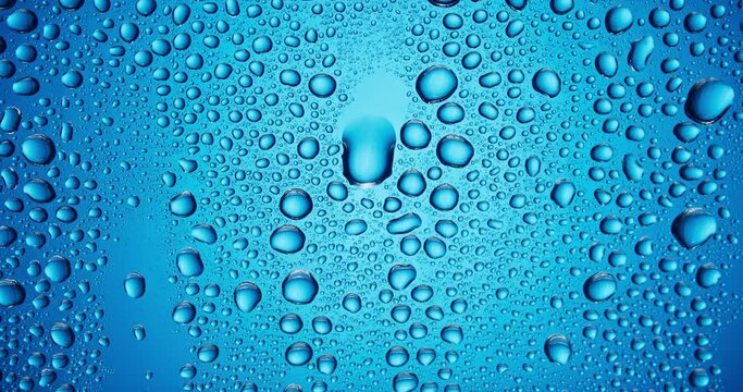 Water droplets falling down the glass surface