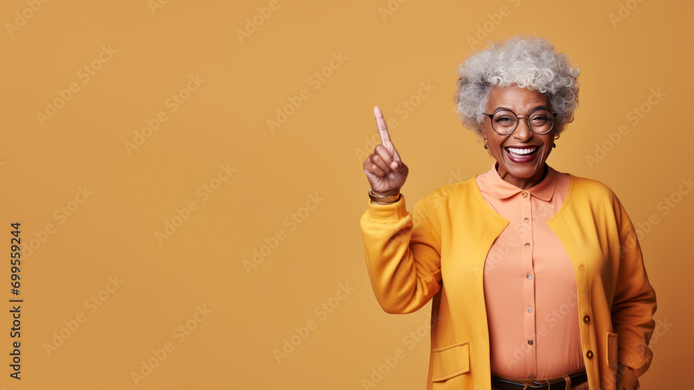 Wall mural Happy senior afro woman points her finger at copy space for promotion