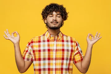 Foto op Plexiglas Young spiritual Indian man he wear shirt casual clothes hold spreading hands in yoga om aum gesture relax meditate try to calm down isolated on plain yellow color background studio. Lifestyle concept © ViDi Studio