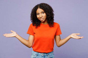 Little doubtful sad kid teen girl of African American ethnicity wear orange t-shirt spread hand...