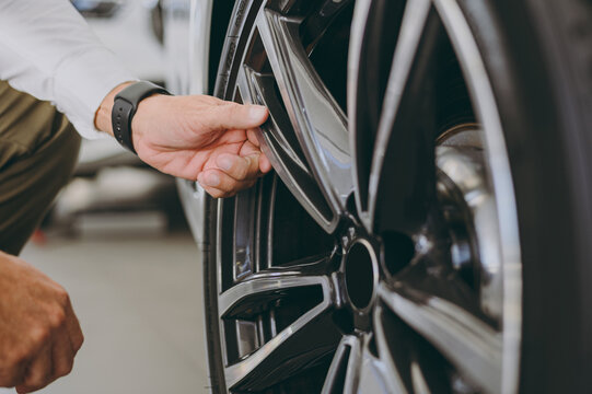 Cropped photo of male customer buyer client open touch gently car wheel rim tire check paint choose auto want buy new automobile in showroom vehicle salon dealership store motor show. Sales concept.