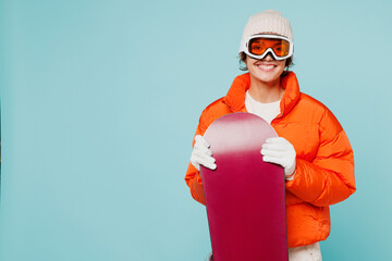 Young confident fun woman wear warm padded windbreaker jacket hat ski goggles mask hold snowboard...