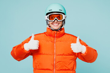 Young satisfied happy skier woman she wear warm padded windbreaker jacket ski goggles mask helmet show thumb up travel rest spend weekend winter season in mountains isolated on plain blue background