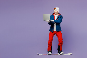Full body IT man in blue windbreaker jacket ski goggles mask hat hold use work on laptop pc...