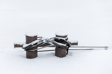 Mooring bollard with steel rope covered with snow, close up