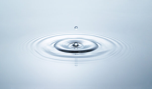 Blue water circles surface with rings and ripples from drops splash