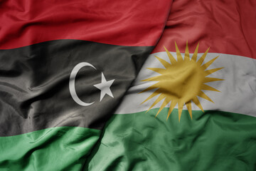 big waving national colorful flag of kurdistan and national flag of libya .