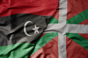 big waving national colorful flag of basque country and national flag of libya .