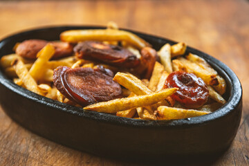 Fried sausages and potatoes in an iron pan