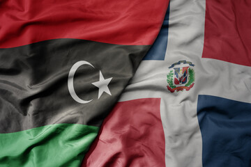 big waving national colorful flag of dominican republic and national flag of libya .