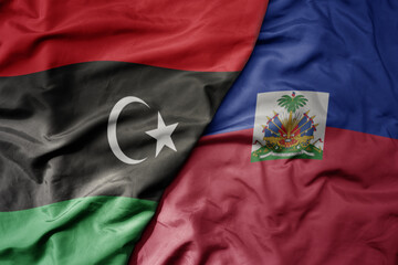 big waving national colorful flag of haiti and national flag of libya .