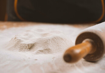 Close-up of a rolling pin and piles of flour with yolk on it