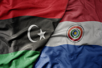 big waving national colorful flag of paraguay and national flag of libya .