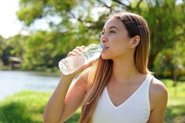 Fitness woman drinking water from bottle. Brazilian Caucasian female drinking water after exercises...